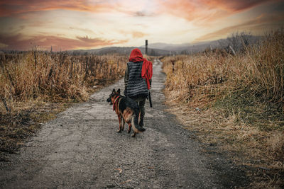 Rear view of woman walking with dog on street