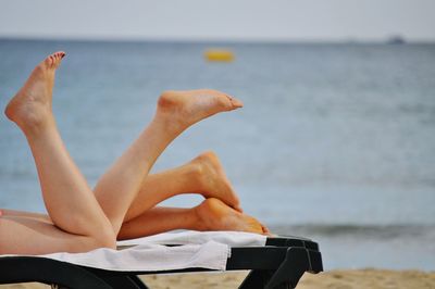 Low section of women relaxing on beach