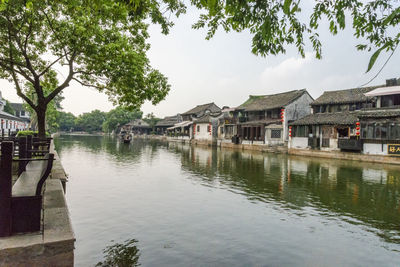 Houses by lake and buildings against sky