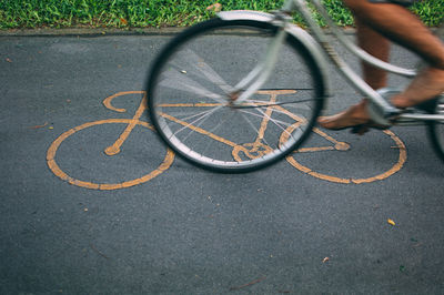 Low section of man riding bicycle on road