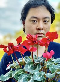 Portrait of young asian man with red flowering cyclamen plant.