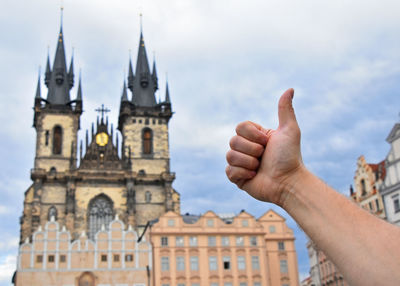Cropped image of hand gesturing against cathedral in city
