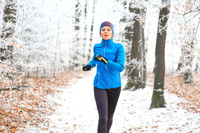 Portrait of woman jogging in forest during winter