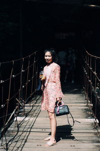 Portrait of young woman standing against railing