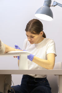 Side view of young woman using mobile phone while sitting at airport