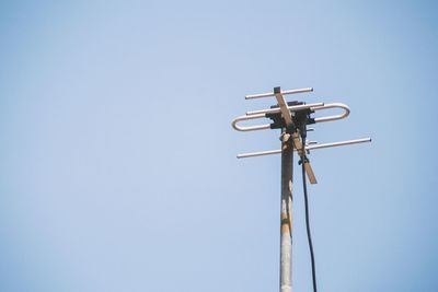 Low angle view of telephone pole against clear blue sky