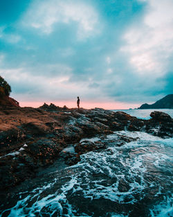 Man standing on rock against sky