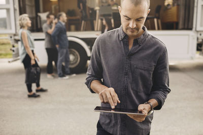 Businessman using digital tablet with colleagues and portable office truck on road in background