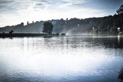 Scenic view of lake by silhouette trees against sky