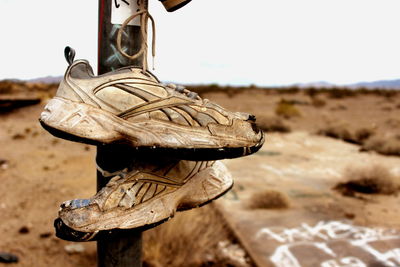 Old shoes hanging on pole at desert