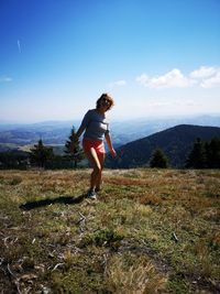 Woman standing on mountain against sky