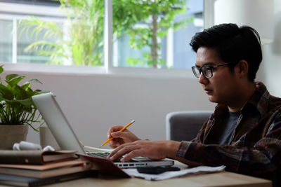 Young man using laptop at home office