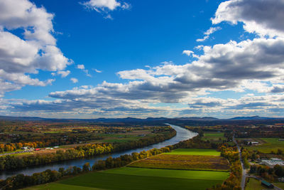 Scenic view of river amidst field against cloudy sky
