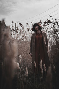 Woman standing on field against sky