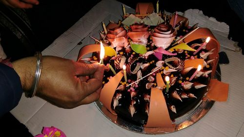 High angle view of hands holding illuminated candles
