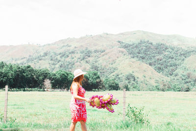 Woman standing on field by mountain against sky