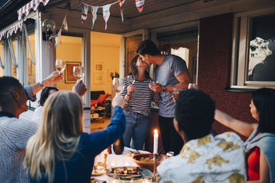 Man and woman kissing during dinner party with friends