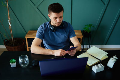 Bored man playing smartphone while working at home office