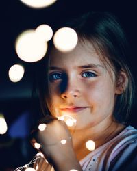 Portrait of girl with illuminated string light in dark at night