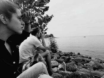 Man with woman by sea looking through binocular