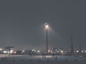 ILLUMINATED STREET LIGHTS AGAINST SKY