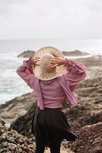 Low section of woman wearing hat on beach against sky