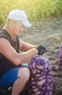 Farmer ties a mesh bag of potatoes. harvesting potatoes on farm plantation. preparing food supplies