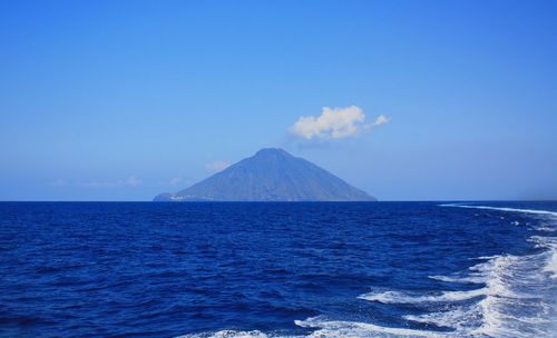 Scenic view of sea and mountains against blue sky