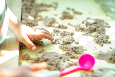 Cropped hand of child playing with sand on table