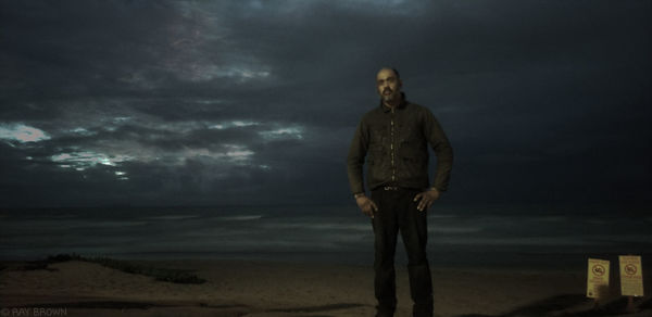 Man standing on beach against sky at dusk