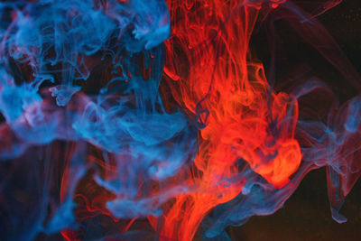 Close-up of red and blue smoke on black background