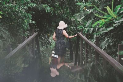 Rear view of woman walking on footbridge in park