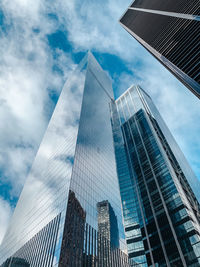 Low angle view of modern buildings against cloudy sky