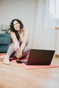 Young woman sitting on hardwood floor at home