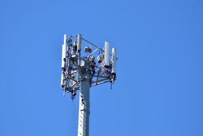 Low angle view of communications tower against clear blue sky