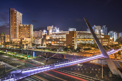 Light trails on bridge in city against sky at night
