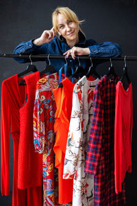 Portrait of woman standing by clothes rack