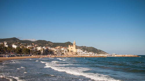 Sea by buildings against clear blue sky