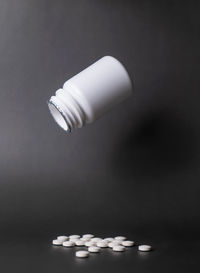 Close-up of pills in bottle against black background