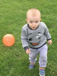 Portrait of cute boy standing on grassy field at park