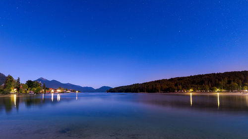 Scenic view of lake against clear blue sky at night