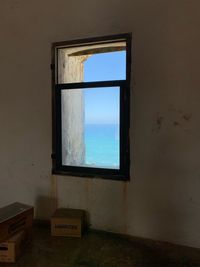 Window on wall by sea against sky