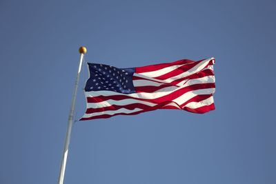 Low angle view of flag against clear blue sky