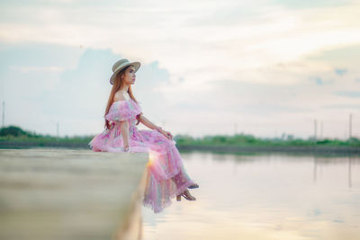 Woman standing on pink water against sky