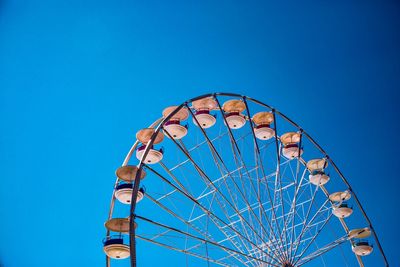 Low angle view of ferris wheel against clear blue sky