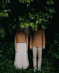 Rear view of couple standing against plants