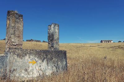 Old ruin on field against clear blue sky