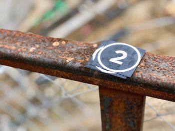 High angle view of paper with number 2 on rusty railing