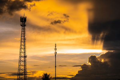 Low angle view of silhouette communications tower against sky during sunset