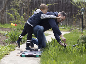 Happy boy with father repairing in garden